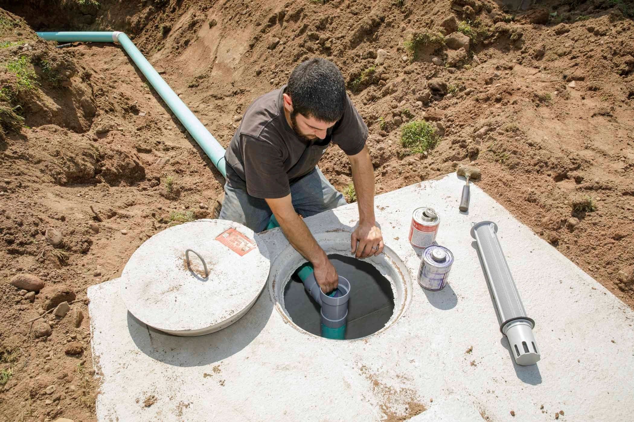 Concrete septic tank installation — a technician working at the open tank lid.