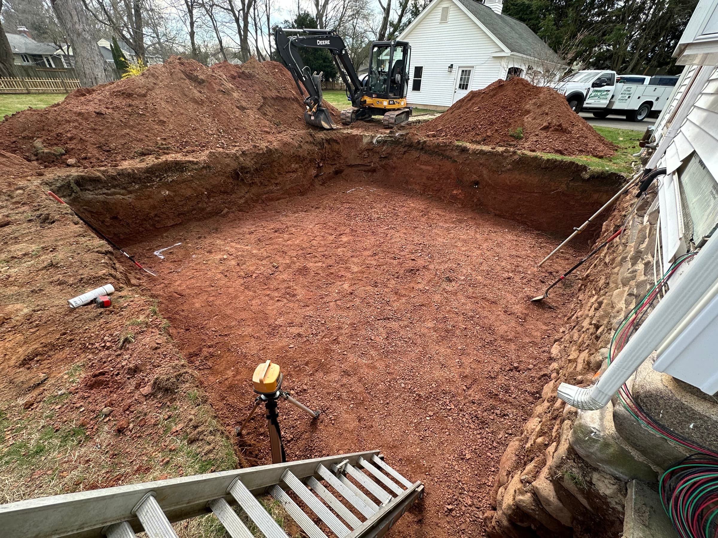 Foundation excavation cut beside a home, ready for footings.