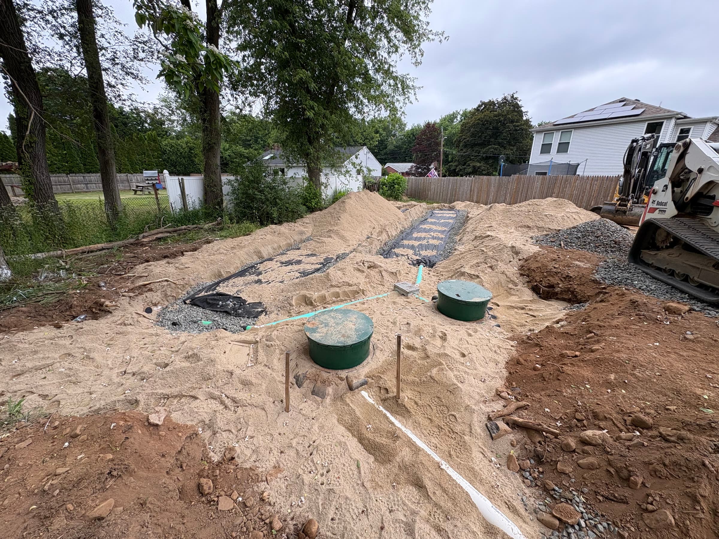 Leaching chambers bedded in C33 sand with access lids and field fabric.